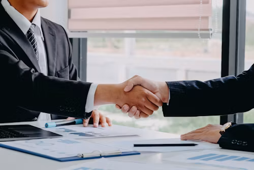 Two people shaking hands across a desk